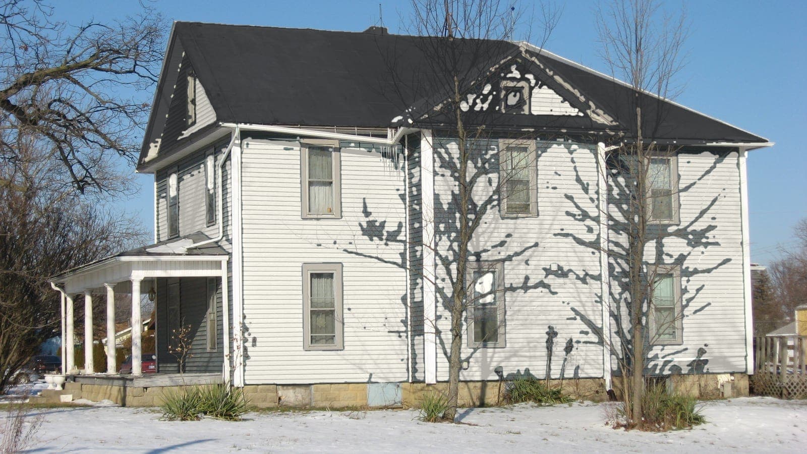 Two-story farmhouse with lap siding and a metal roof, repainted: siding Alabaster SW 7008, roof Charcoal (shingle)