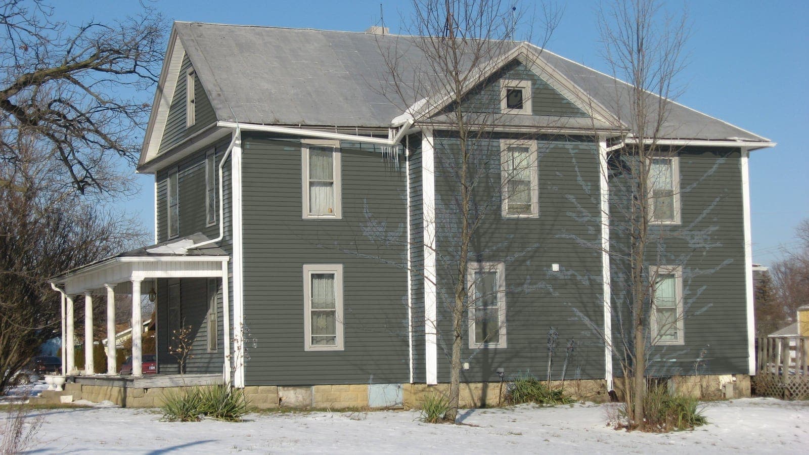 Two-story farmhouse with lap siding and a metal roof, repainted: siding Pewter Green SW 6208